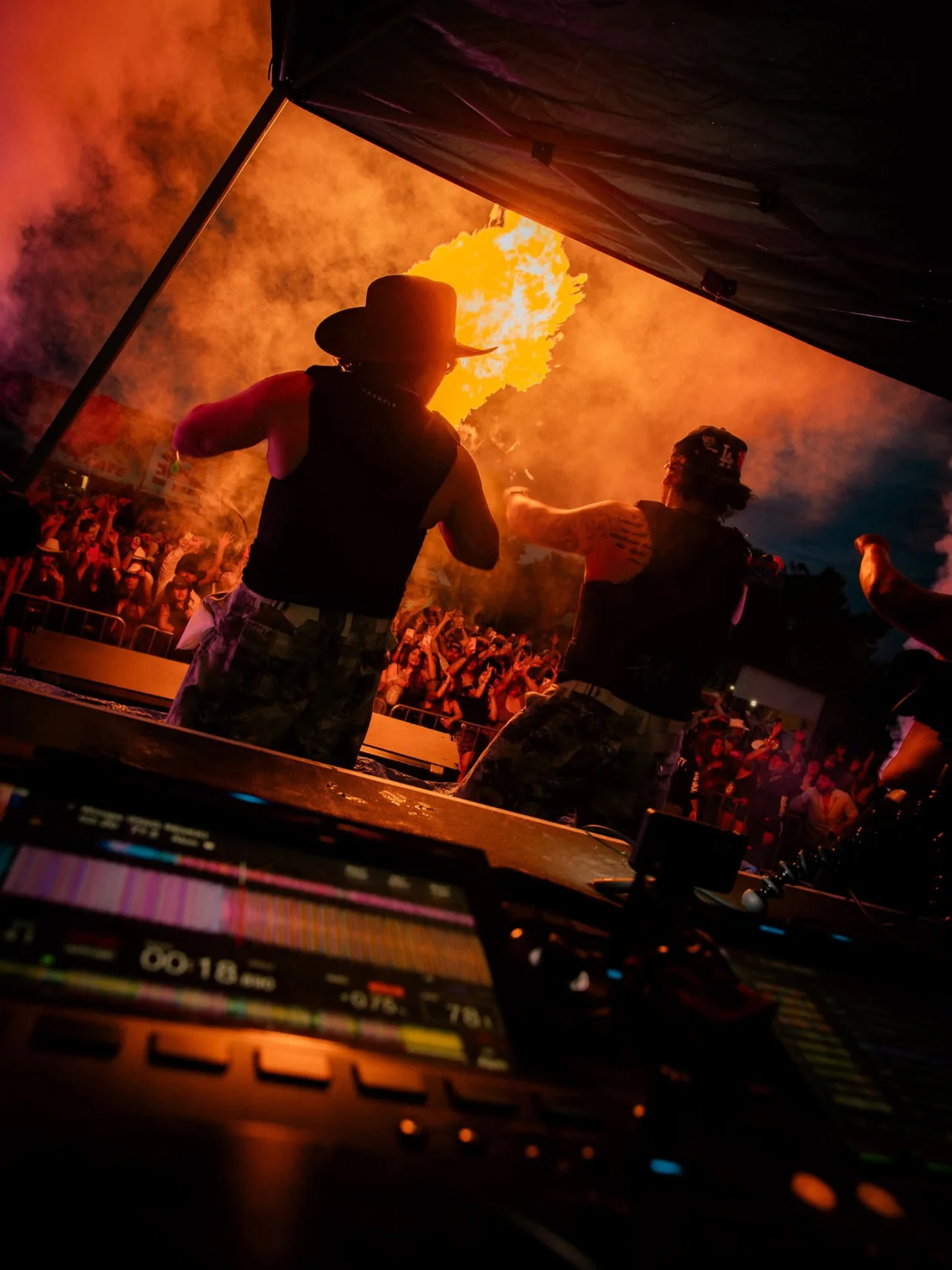 A view from behind a performer toward an orange-lit concert crowd